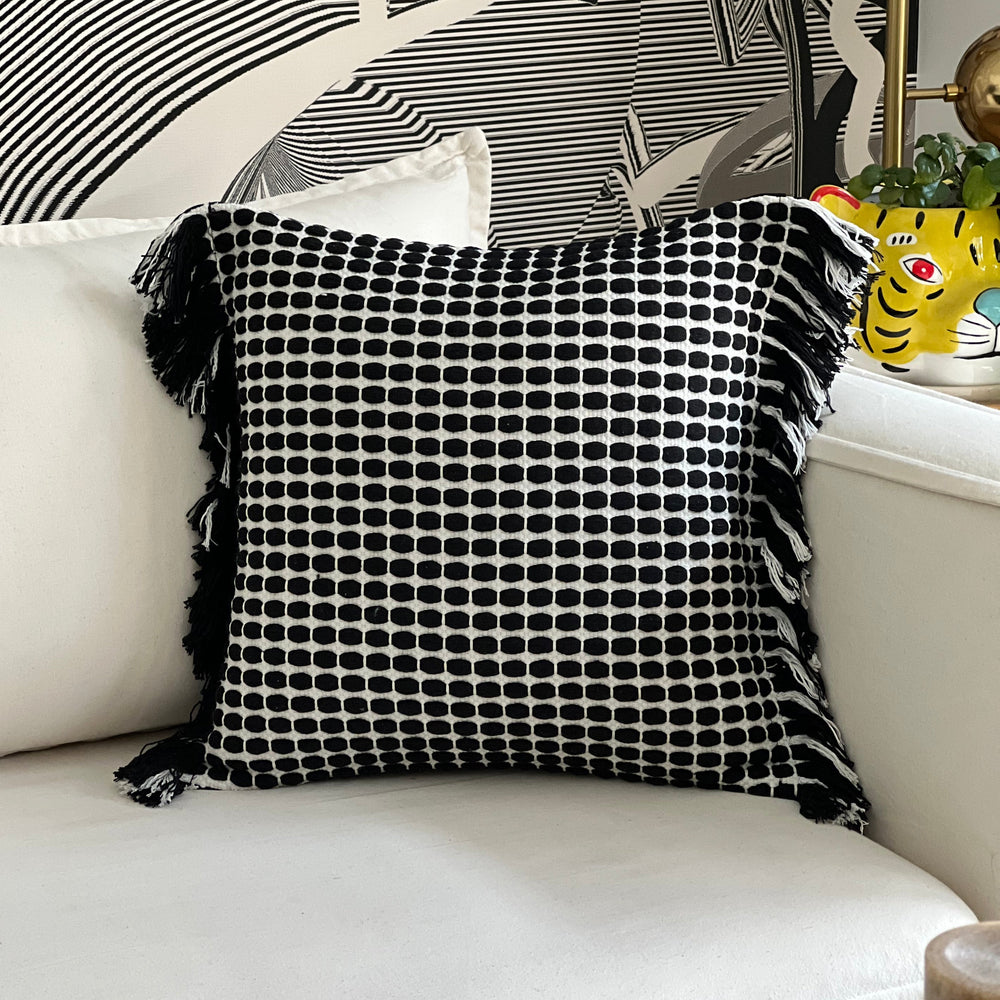 Cojín negro decorativo sobre sillón estilo moderno y acogedor